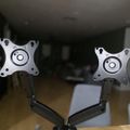 Dual monitor arm mount with adjustable brackets on wooden desk