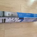 A TV wall mount product box lying on a wooden floor, showing packaging with product images and specifications
