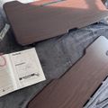 Two dark wood-grain laptop desk trays with instruction manual on gray fabric surface