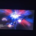 A video game loading screen showing spaceships in a colorful space scene with blue and red lighting effects, with "VENDORS" text and game instructions visible in the lower left corner.