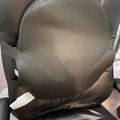 A black mesh lumbar support cushion placed on a dark leather office chair