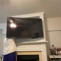 Living room with white fireplace mantel, mounted flat screen TV above, and electric fireplace insert below