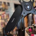 A black adjustable monitor or tablet mount arm positioned on a desk in an office or workspace setting