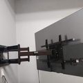 Wall-mounted TV with articulating bracket arm extended in corner of white room
