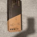 A black and orange product box for a monitor desk mount lying on a beige carpet