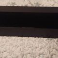 Black rectangular TV stand or media console with open shelving compartments on a marble floor