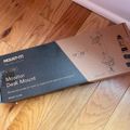 A MOUNT-IT! Monitor Desk Mount product box on a wooden floor, showing packaging for a 17-32 inch monitor mount with ergonomic workspace features