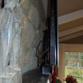 Interior room with stone wall, exposed ceiling beams, mounted TV, and window overlooking outdoor scenery