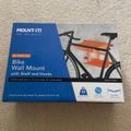 Package for a Mount-It bike wall mount with shelf and hooks, showing a black bicycle mounted on an orange wall-mounted storage system