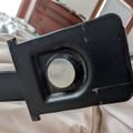 Black plastic device component with circular metallic element and threaded adjustment screw, appears to be part of equipment or machinery