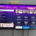 Roku TV home screen displaying menu options including Live TV, Featured Free, Sports, and various HDMI input selections, with streaming app icons visible