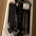 Black tactical equipment and accessories packed in white foam padding inside a cardboard box