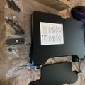 Unboxed black electronic device or equipment with instruction manual and various accessories laid out on carpet