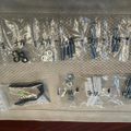 A clear plastic organizer with multiple compartments containing various small hardware items like screws, bolts, and other fasteners sorted into separate sealed bags