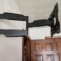 Wall-mounted TV bracket extending over a wooden door frame