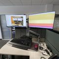Office desk setup with dual monitors, keyboard, mouse and phone in a cubicle workspace