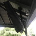 Person working on wooden ceiling beams of an outdoor structure with patio furniture visible below