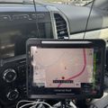 Car dashboard with mounted tablet displaying GPS navigation map showing road routes and coordinates