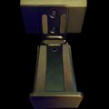 A metallic device or fixture with circular lights at the top and a rectangular base, photographed against a dark background