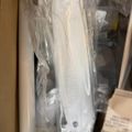 White kitchen appliance or tool in plastic packaging stored in a cabinet or drawer