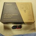 A boxed Mount-It 360 degree swivel pegboard and organizer with accessories sits on beige carpet next to a small black and red multi-tool, with part of a blue fabric visible in the corner
