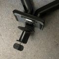 Black adjustable clamp or vise mechanism with threaded screw handle on concrete floor