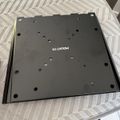 A black rectangular mounting plate with multiple holes and "MOUNT-IT" text, placed on a striped fabric surface