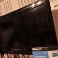 A flat-screen TV mounted on a wall above decorative beaded necklaces and a low-profile TV wall mount box visible below it.