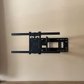 Black TV wall mount bracket installed on white wall above wooden surface