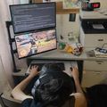 Person sitting at desk using dual monitor computer setup in home office with bulletin board and office equipment visible