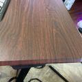 A wooden table with rich brown grain patterns on a decorative metal base, sitting on a patterned area rug