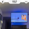 A TV screen displaying animated cartoon characters that appear to be from the children's show Bluey, showing colorful orange and blue dog characters in a scene.