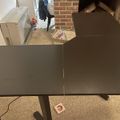 A dark wooden dining table with extension leaves open, positioned on a beige carpet in a room with brick walls and white cabinets