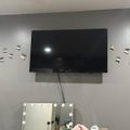 Wall-mounted TV above a lighted vanity mirror with decorative butterfly wall decals