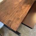 A wooden table with an extendable leaf pulled out, showing the extension mechanism on a carpeted floor