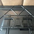 TV wall mount bracket with adjustable arms lying on a glass coffee table