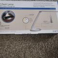 LED desk lamp product box showing wireless charging base and adjustable brightness features on gray carpet