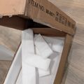 An open cardboard shipping box with item number MI-8671 printed on top, containing white foam packing materials and protective padding inside, sitting on a wooden floor.