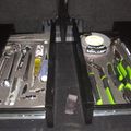 Two organized tool trays containing various hand tools including wrenches, screwdrivers, and measuring tape arranged on a dark surface