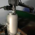 Professional studio microphone with shock mount on adjustable boom arm positioned over desk workspace