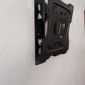 Black adjustable TV wall mount bracket attached to white wall