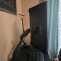 A computer workstation with a monitor on an adjustable arm mount, keyboard, and desk setup near a window with curtains