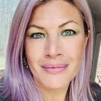 Woman with purple-tinted hair and colorful eye makeup taking a selfie