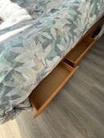 Customer-uploaded image. Click to see more details. The image represents: A wooden bed frame with storage drawers underneath, featuring a mattress with a leaf-patterned upholstered headboard in shades of green and beige, positioned on a gray wood-look floor.
