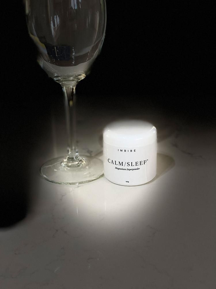 A CALM/SLEEP jar beside an empty glass in dramatic evening light