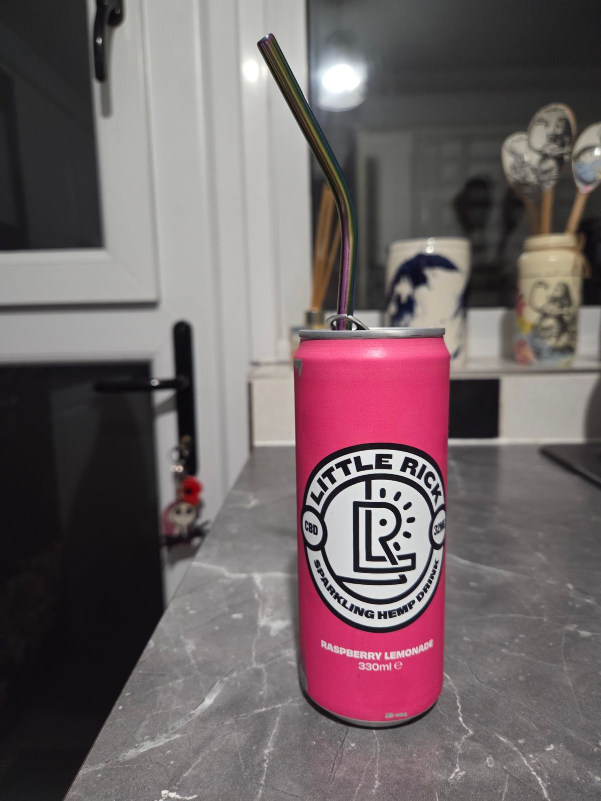 Pink can of Little Rick sparkling hemp drink with rainbow straw on kitchen counter
