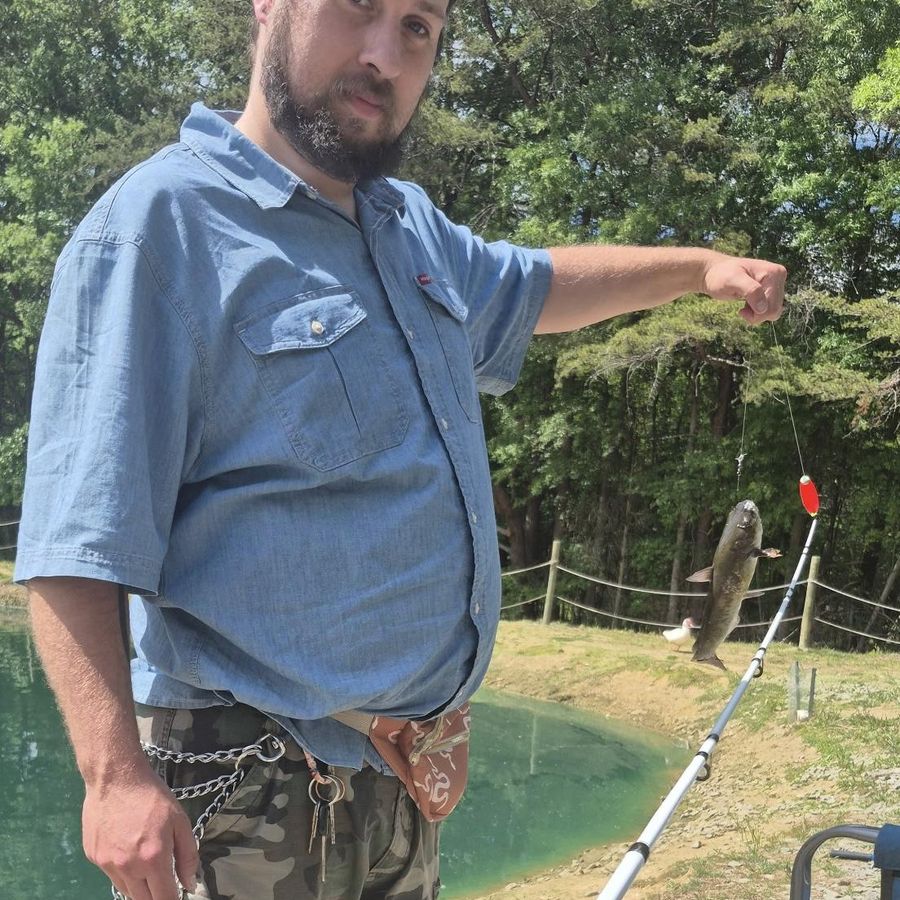 A white, straight sized man wears his fanny pack while fishing.