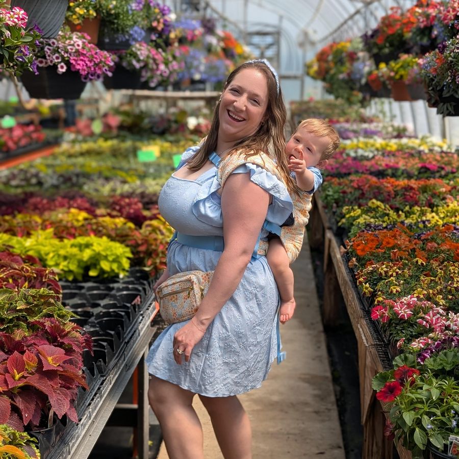 A white, straight sized woman wears her fanny pack while babywearing in a back carry.