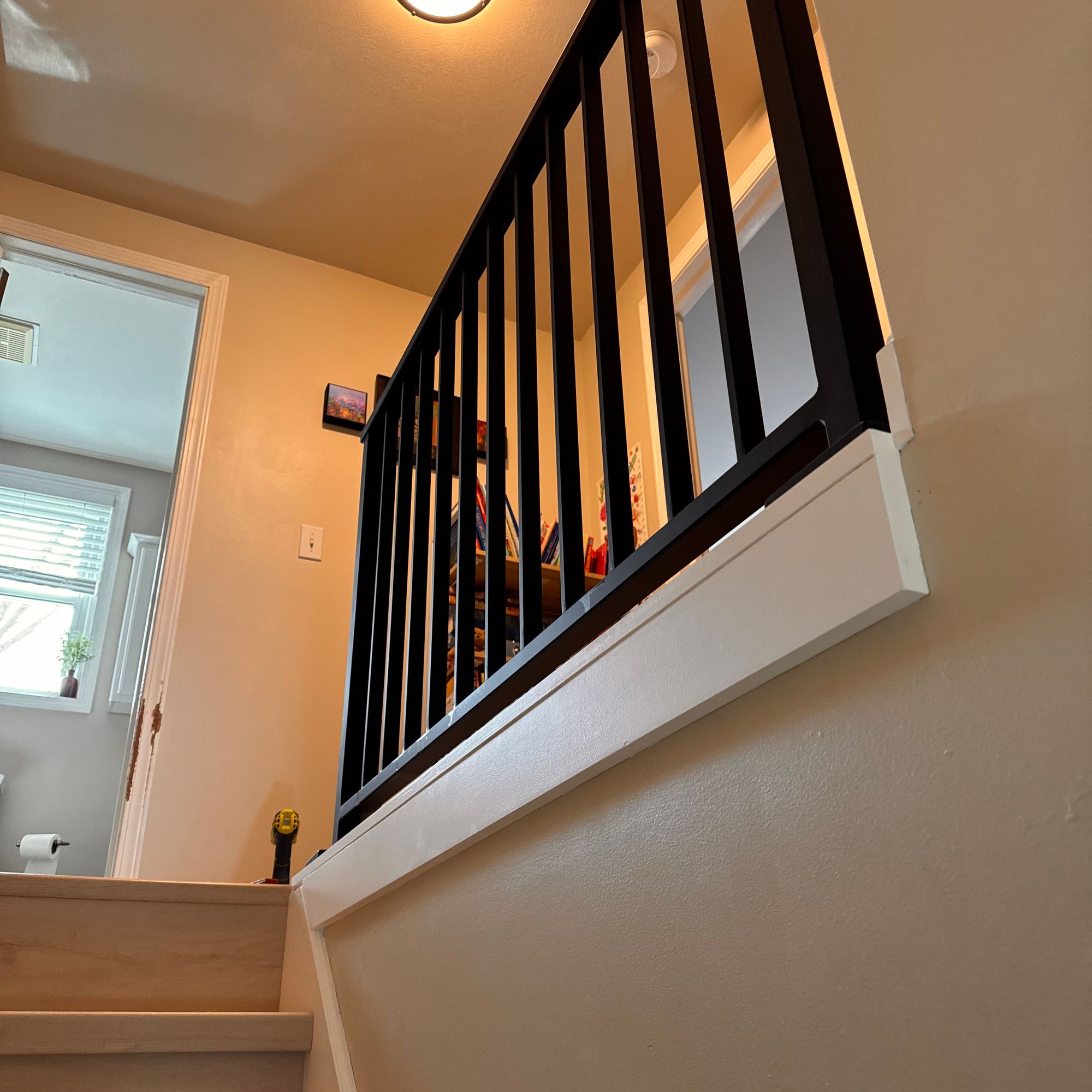 Interior staircase with white steps and black metal railings leading to upper floor, with circular ceiling light fixture above