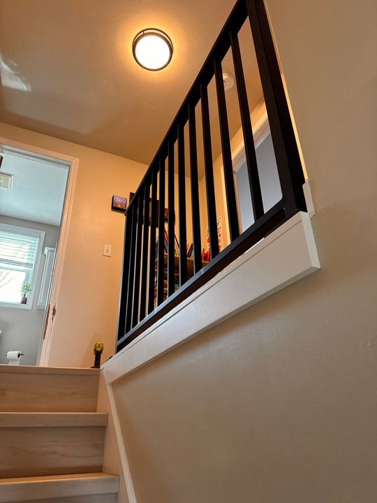 Interior staircase with white steps and black metal railings leading to upper floor, with circular ceiling light fixture above